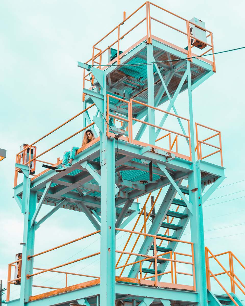 structure woman sitting on teal and yellow metal tower during daytime richmond